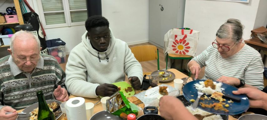 Un groupe de trois personnes partage un repas convivial à une table, avec de la nourriture dispersée.